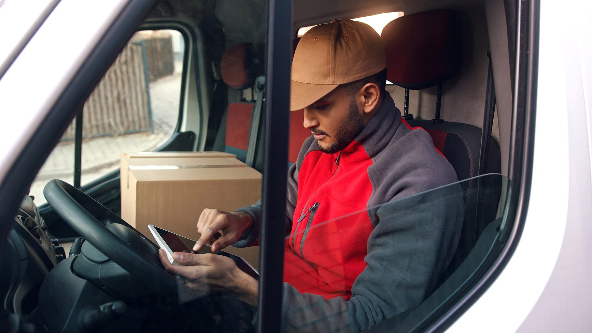 A delivery driver using a tablet while sitting inside a van. A delivery driver using a tablet while sitting inside a van.