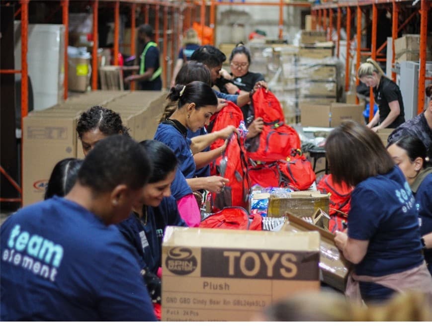 Team members packing backpacks and supplies in a warehouse. Team members packing backpacks and supplies in a warehouse.