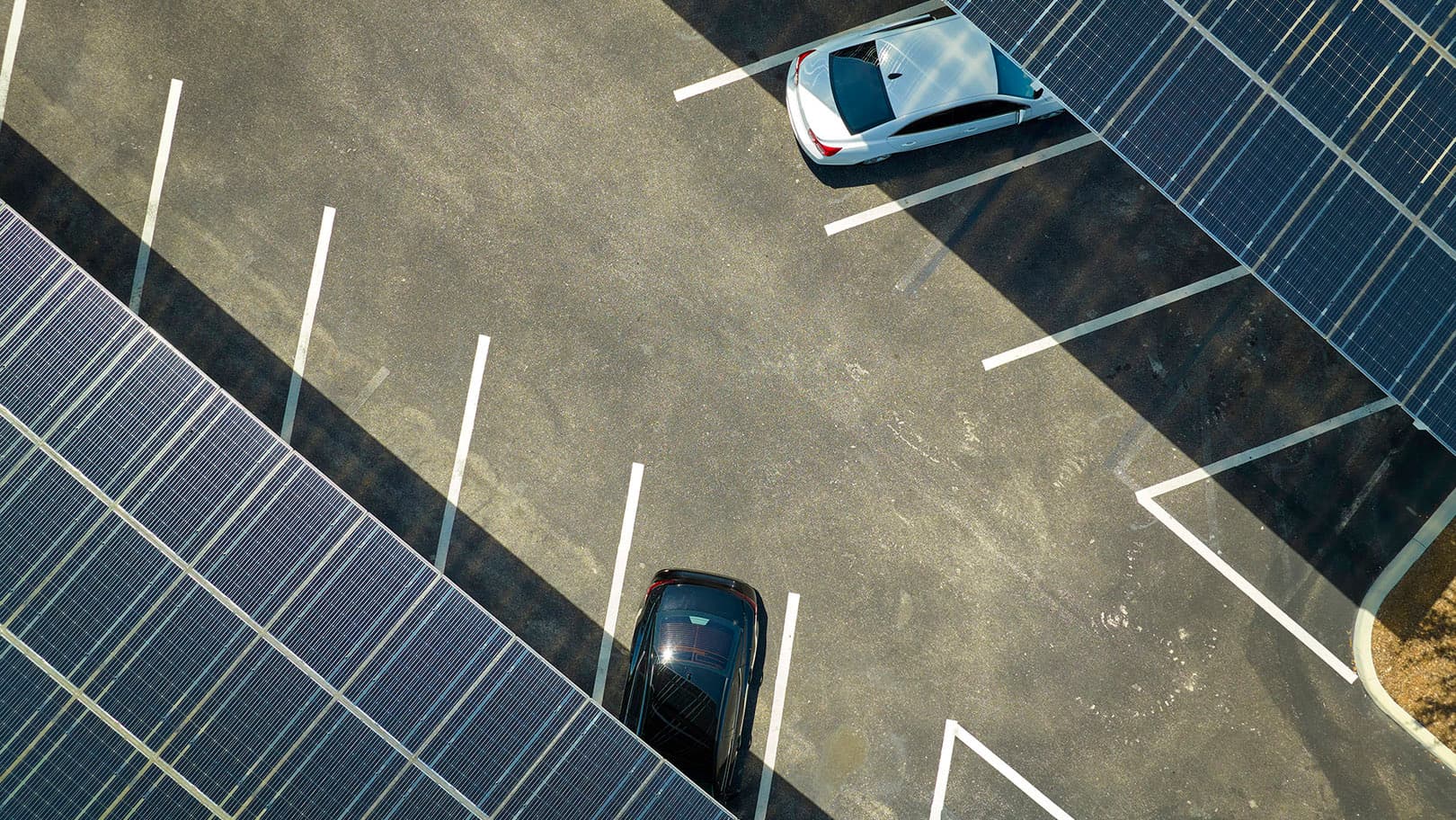 Fleet vehicles parked beneath solar panel canopies in a commercial parking lot. Fleet vehicles parked beneath solar panel canopies in a commercial parking lot.