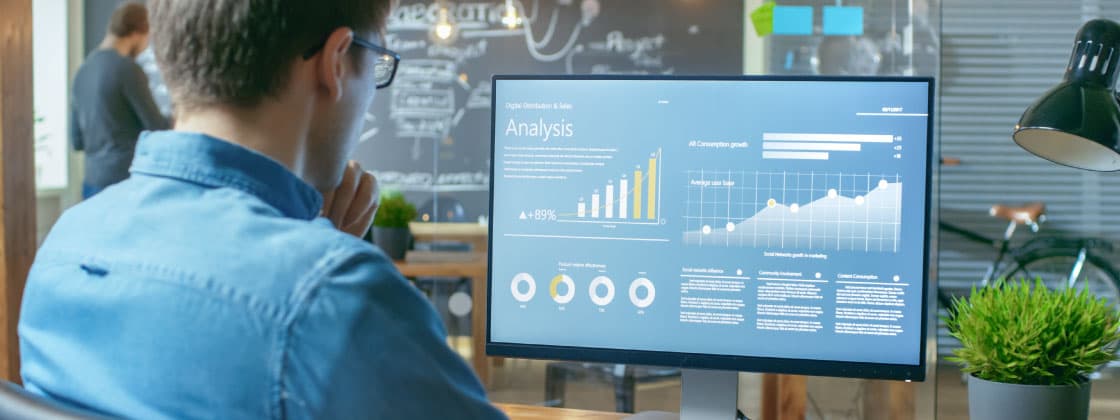Man reviewing analytics on monitor Man reviewing analytics on monitor