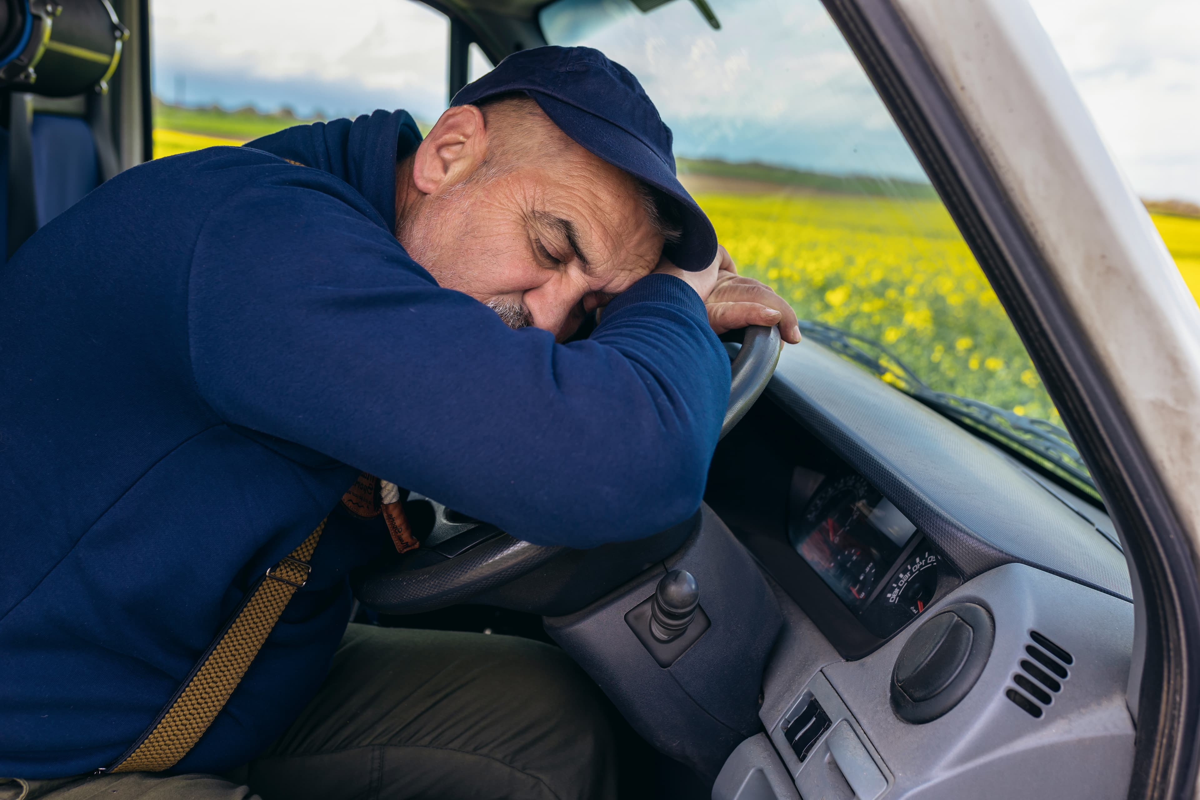 Fatigued fleet driver falling asleep behind the steering wheel of a commercial vehicle. Fatigued fleet driver falling asleep behind the steering wheel of a commercial vehicle.