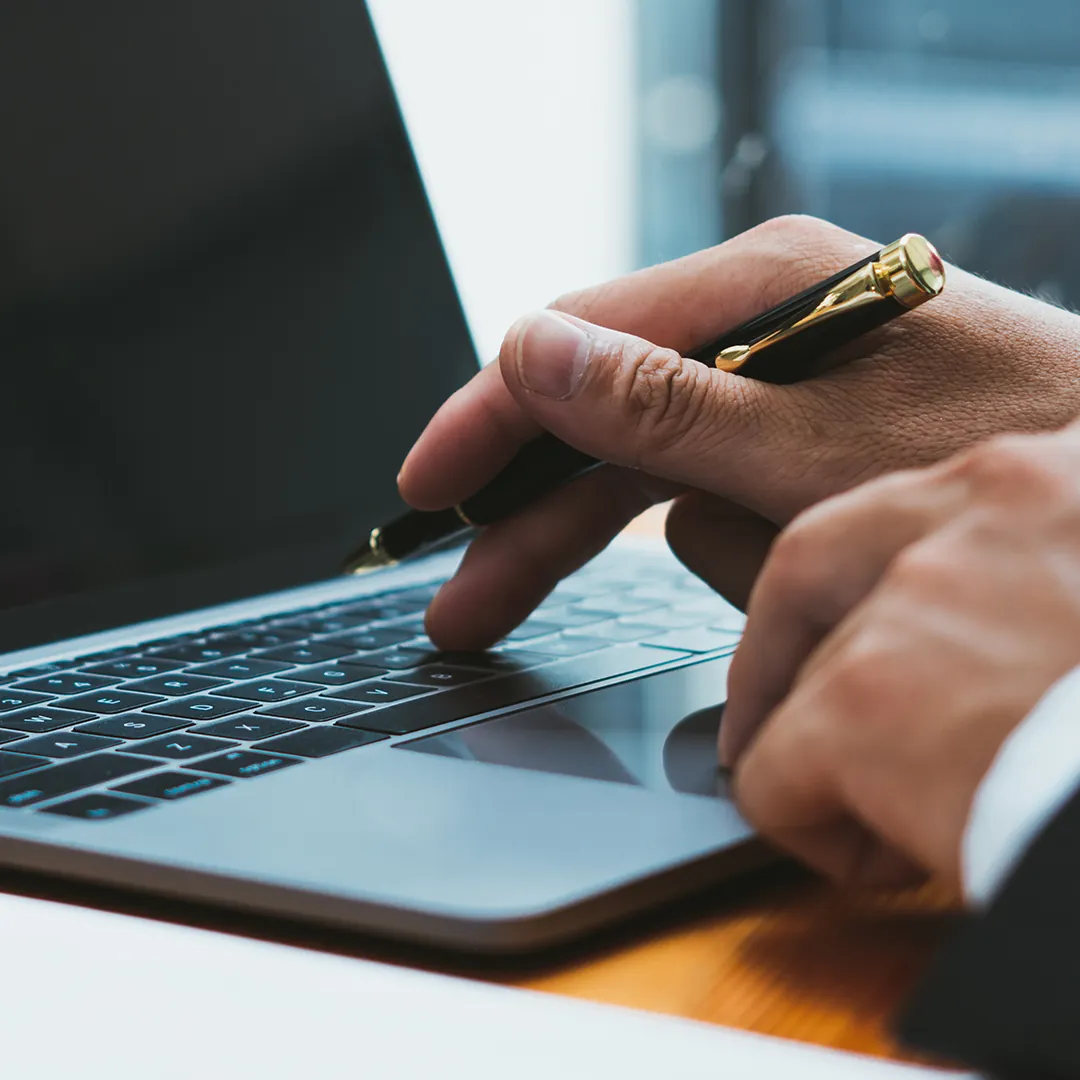 A person's hand holding a black and gold pen. A person's hand holding a black and gold pen.