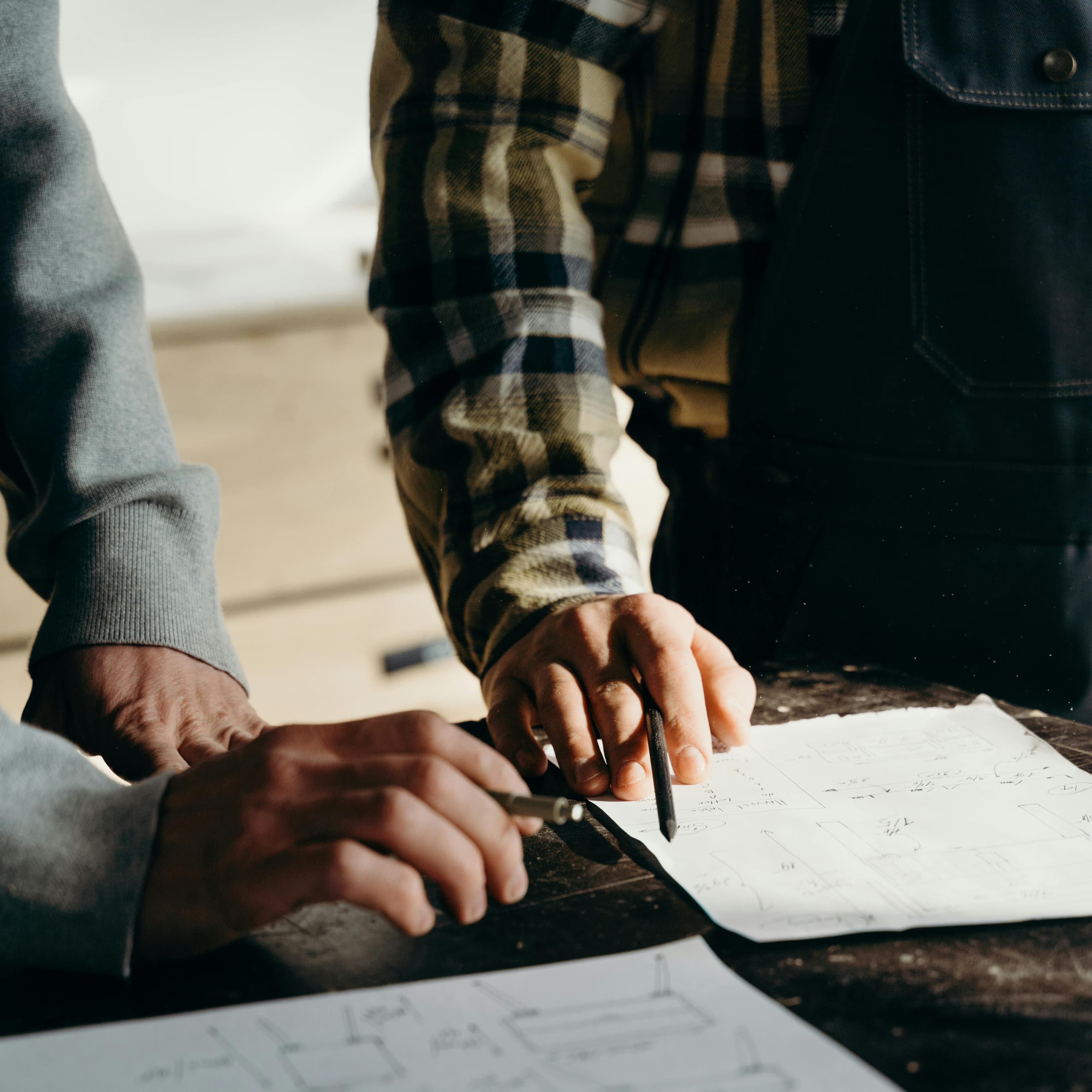 Workers reviewing blueprint drawings together at a construction site. Workers reviewing blueprint drawings together at a construction site.
