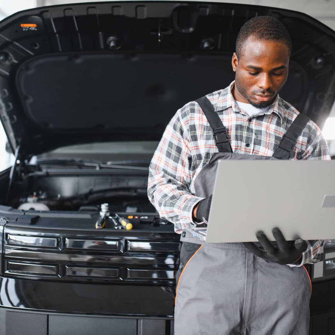Automotive technician using a laptop to perform vehicle diagnostics during fleet maintenance. Automotive technician using a laptop to perform vehicle diagnostics during fleet maintenance.